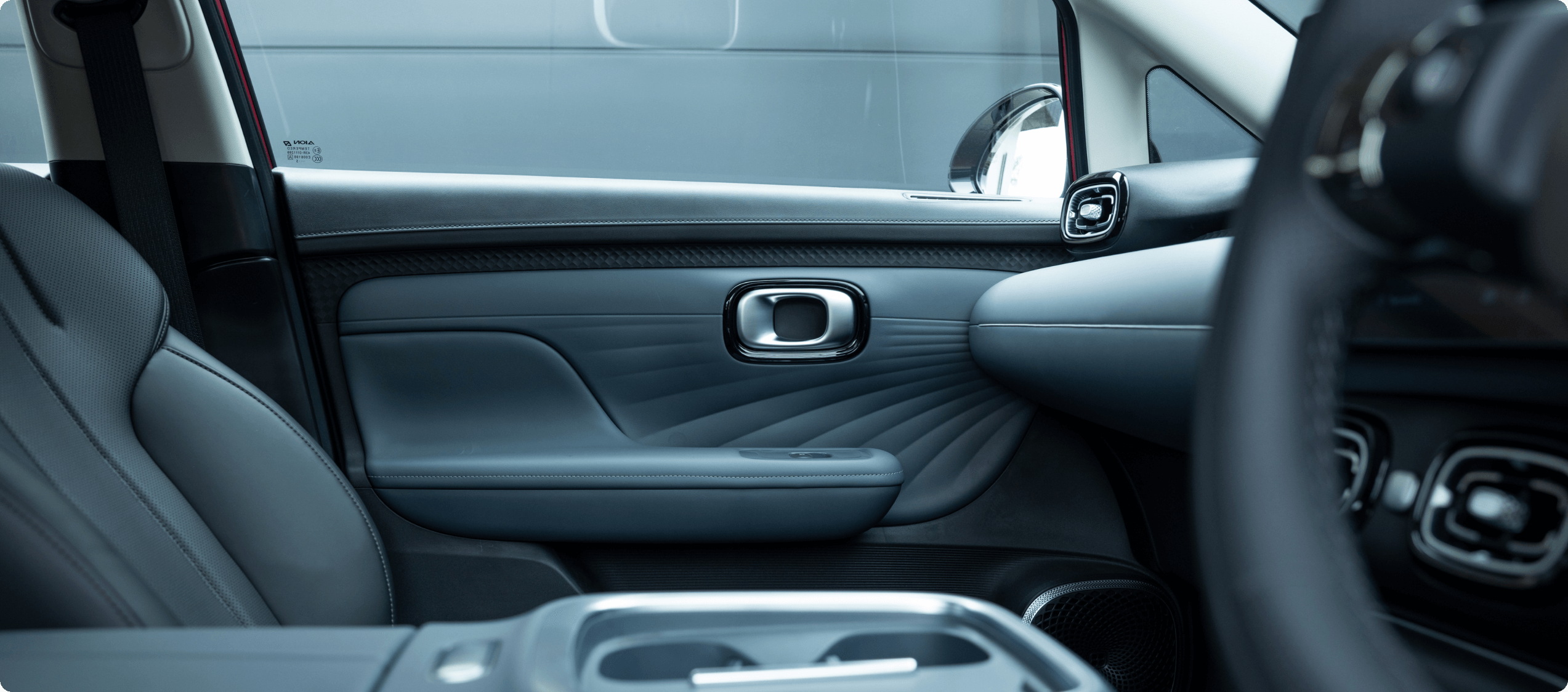Interior door panel of the AION UT showing textured trim, armrest and door handle