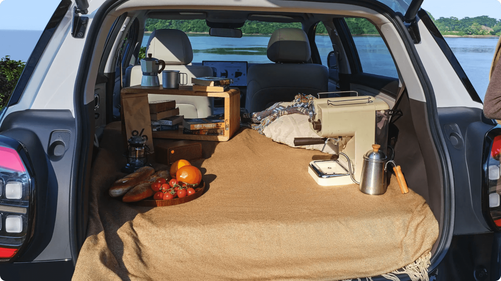 Rear of the AION UT with seats folded flat, showing the boot set up for camping and storage