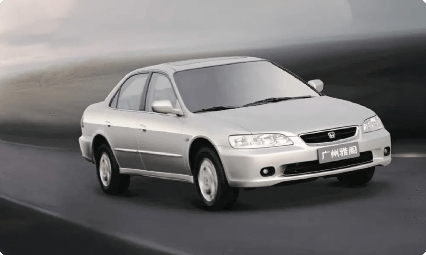 Silver four-door sedan driving on a road