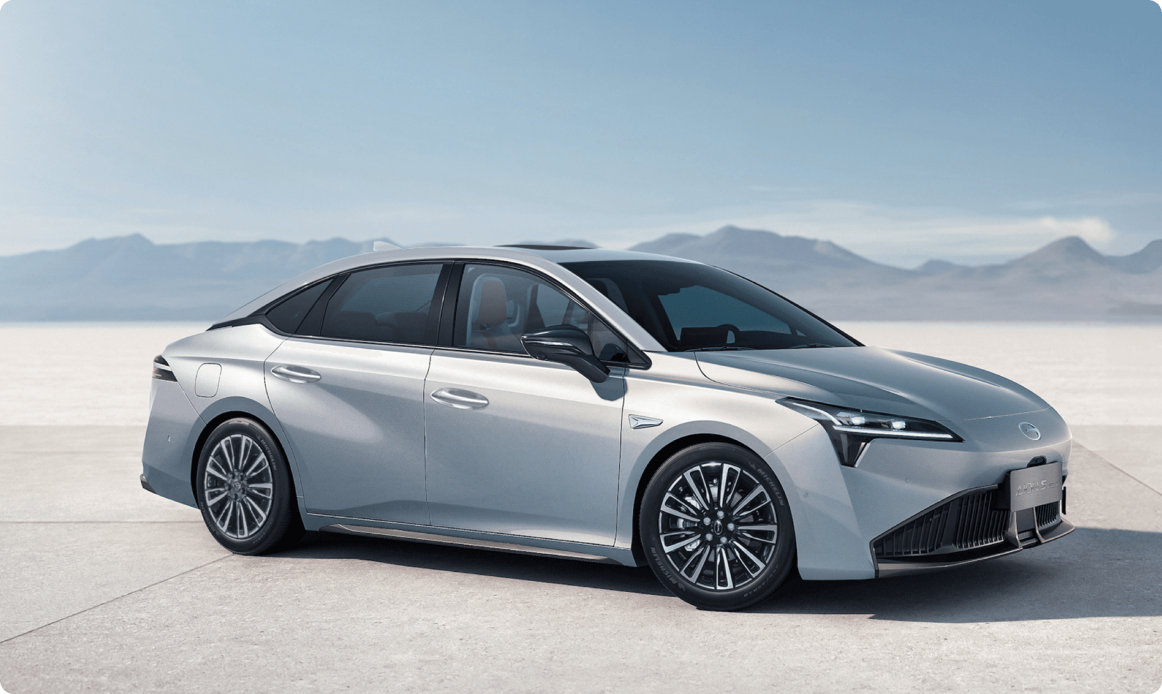 AION sedan shown from the side against a minimal landscape backdrop