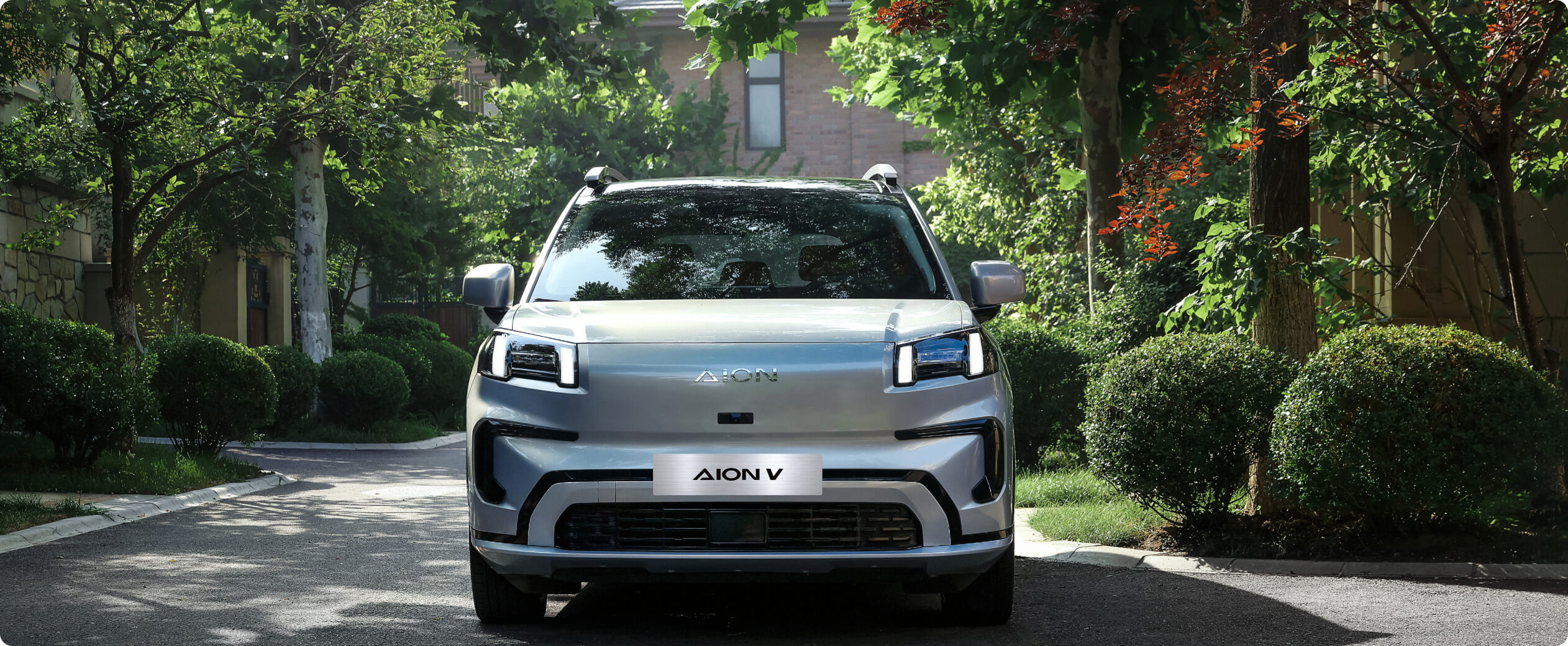 Front view of a AION V parked on a tree-lined residential street