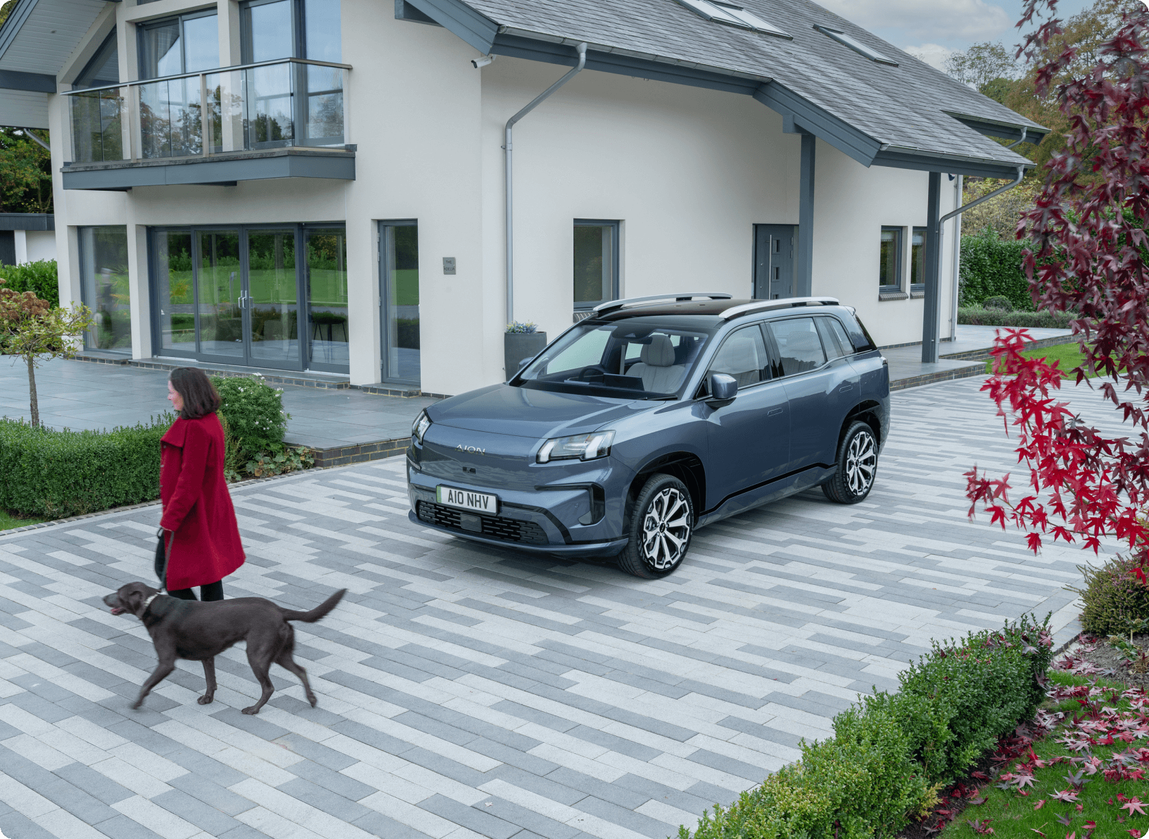 AION V parked outside a modern home while a person walks a dog along the driveway