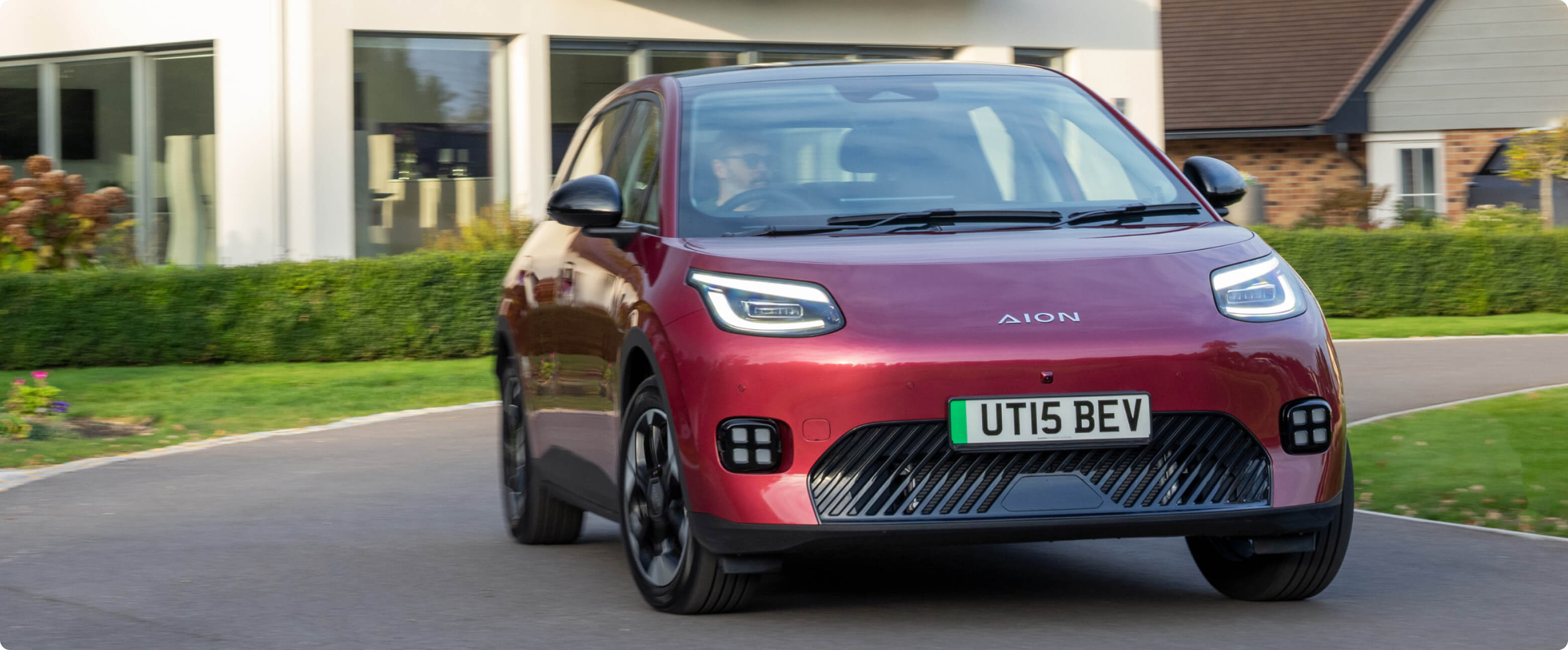 AION UT driving on a residential road past modern homes