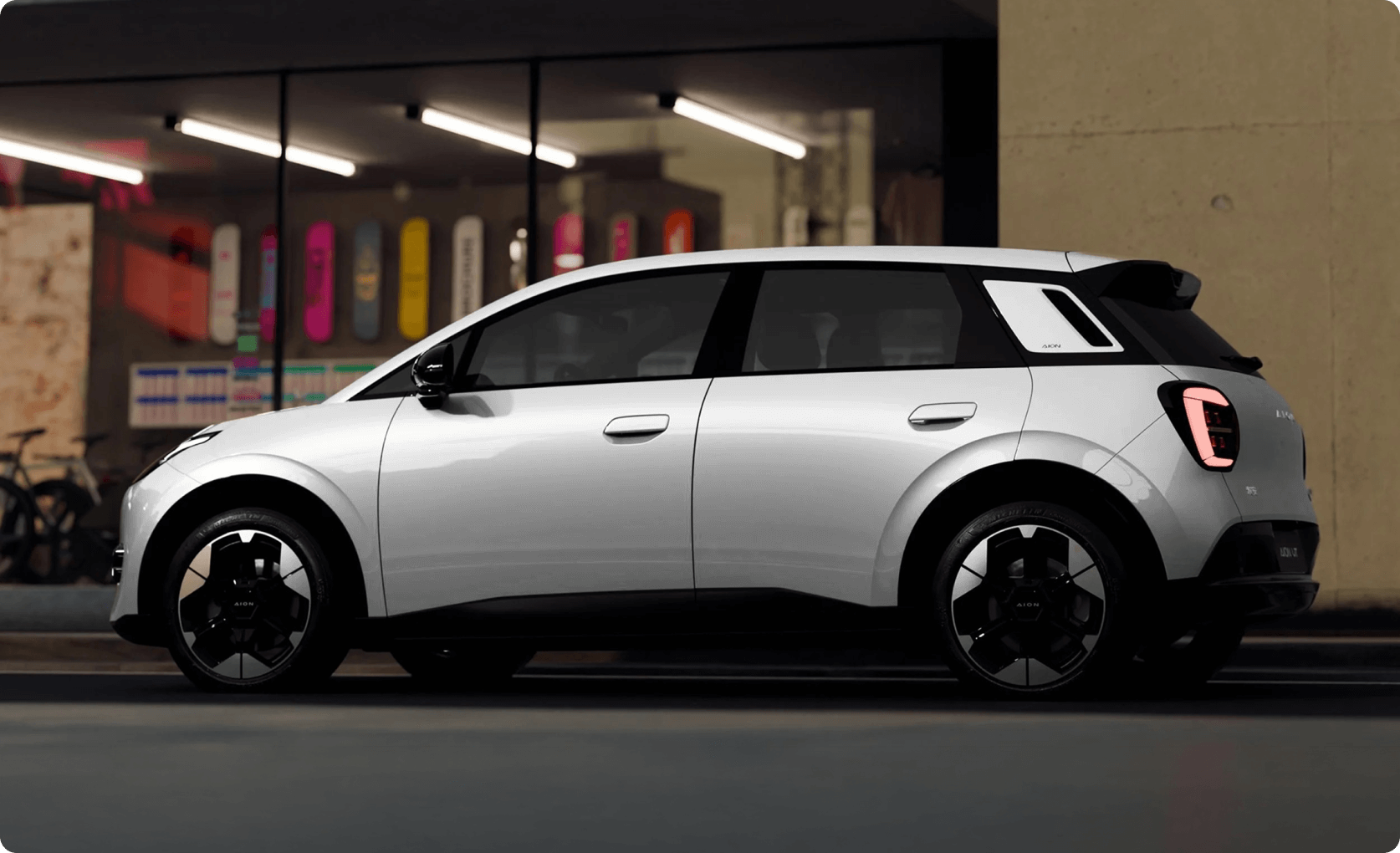 Side profile of the AION UT parked outside a modern building at night