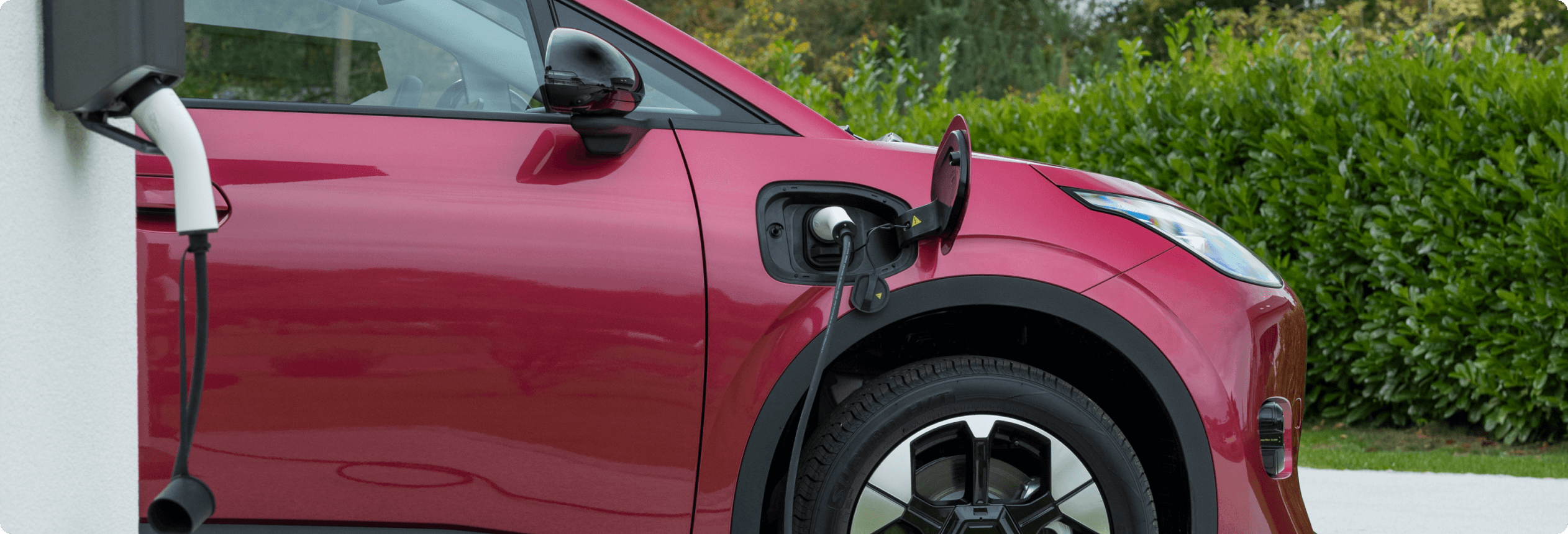 AION UT charging at a home wall charger on a driveway