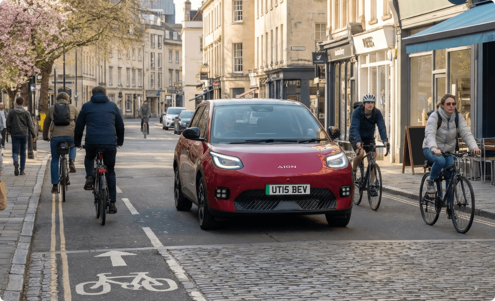 Red AION UT driving through a city street alongside cyclists and pedestrians