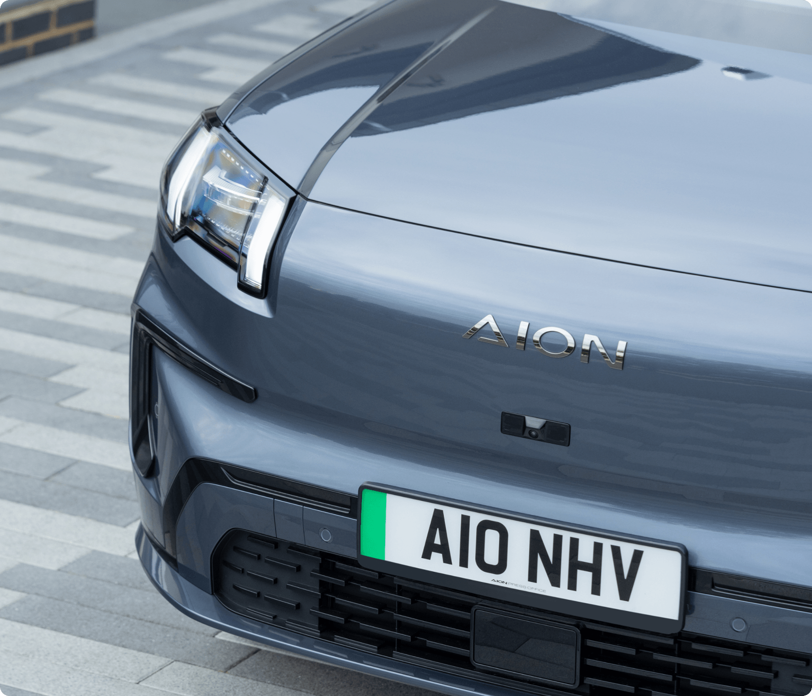 Close-up of the front of the AION V showing the headlight, badge, and grille