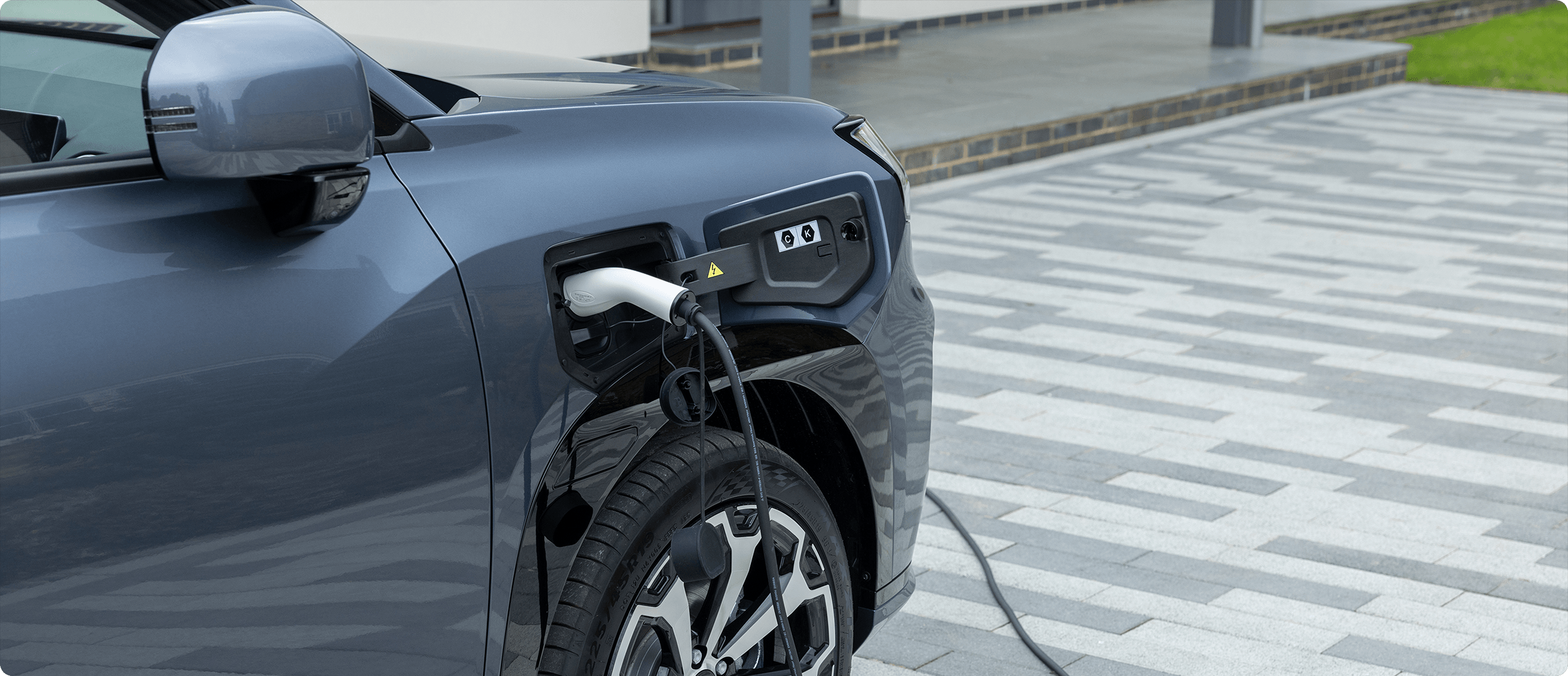 AION V plugged into a home charging point on a residential driveway