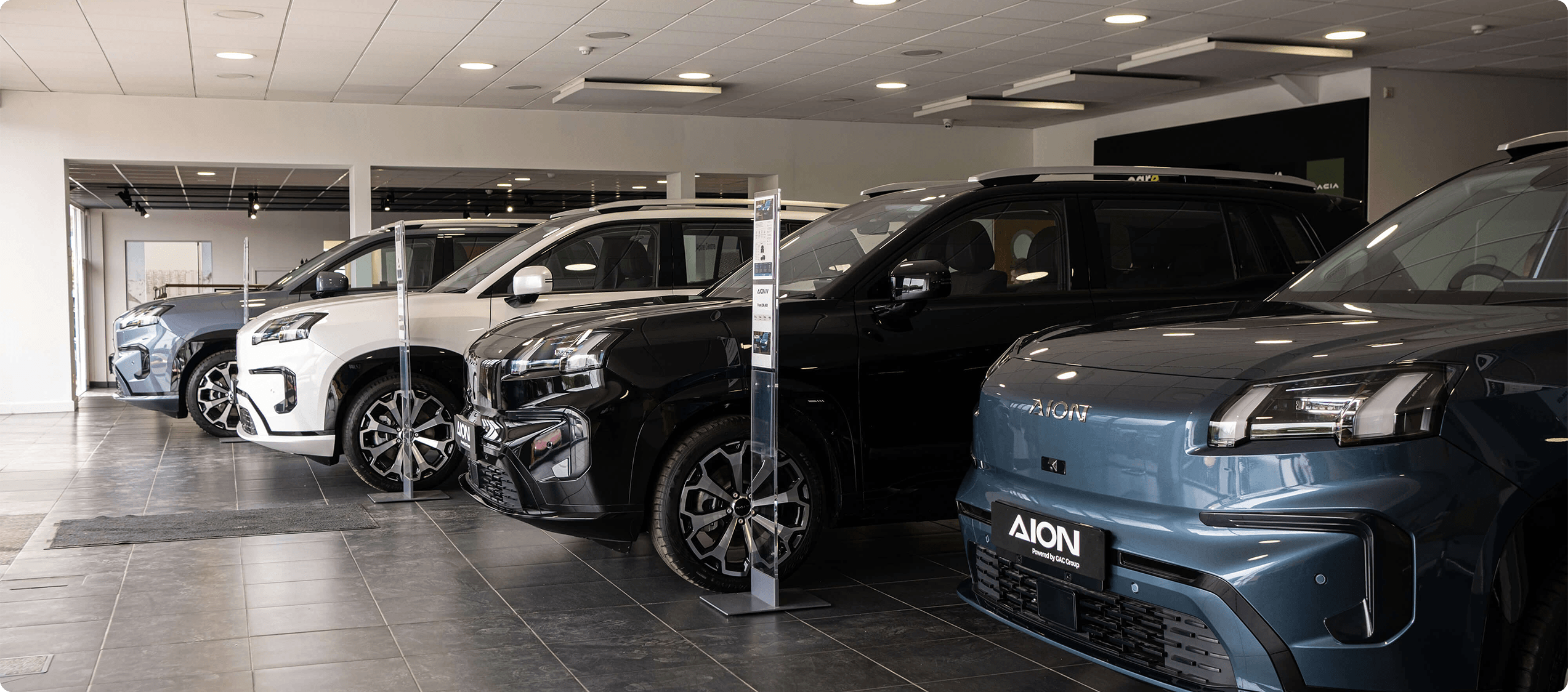 Inside view of AION dealership showing the side of three AION V