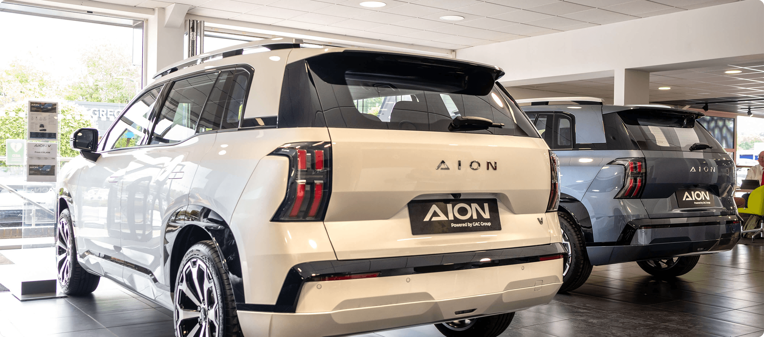 Inside view of AION dealership showing the back of two AION V