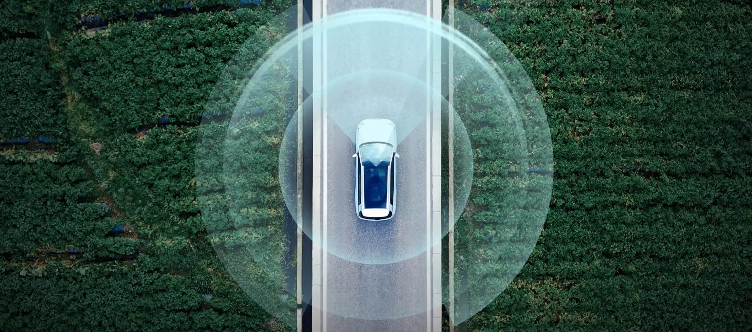 Top-down view of an AION vehicle on a road, with graphic overlays illustrating its surrounding sensor coverage